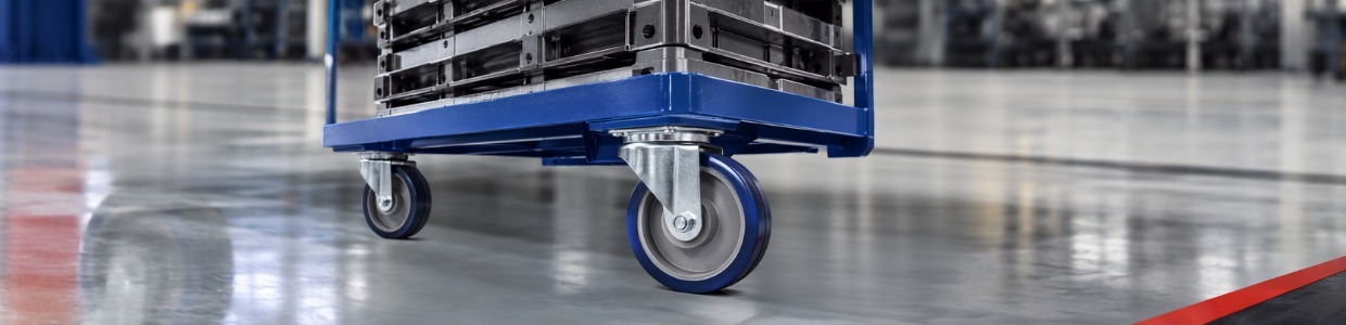 Heavy-duty platform trolley with industrial castor wheels transporting heavy metal loads in a manufacturing facility | Rexello Castor